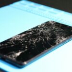 A cracked smartphone screen on a repair mat highlights technology mishaps.
