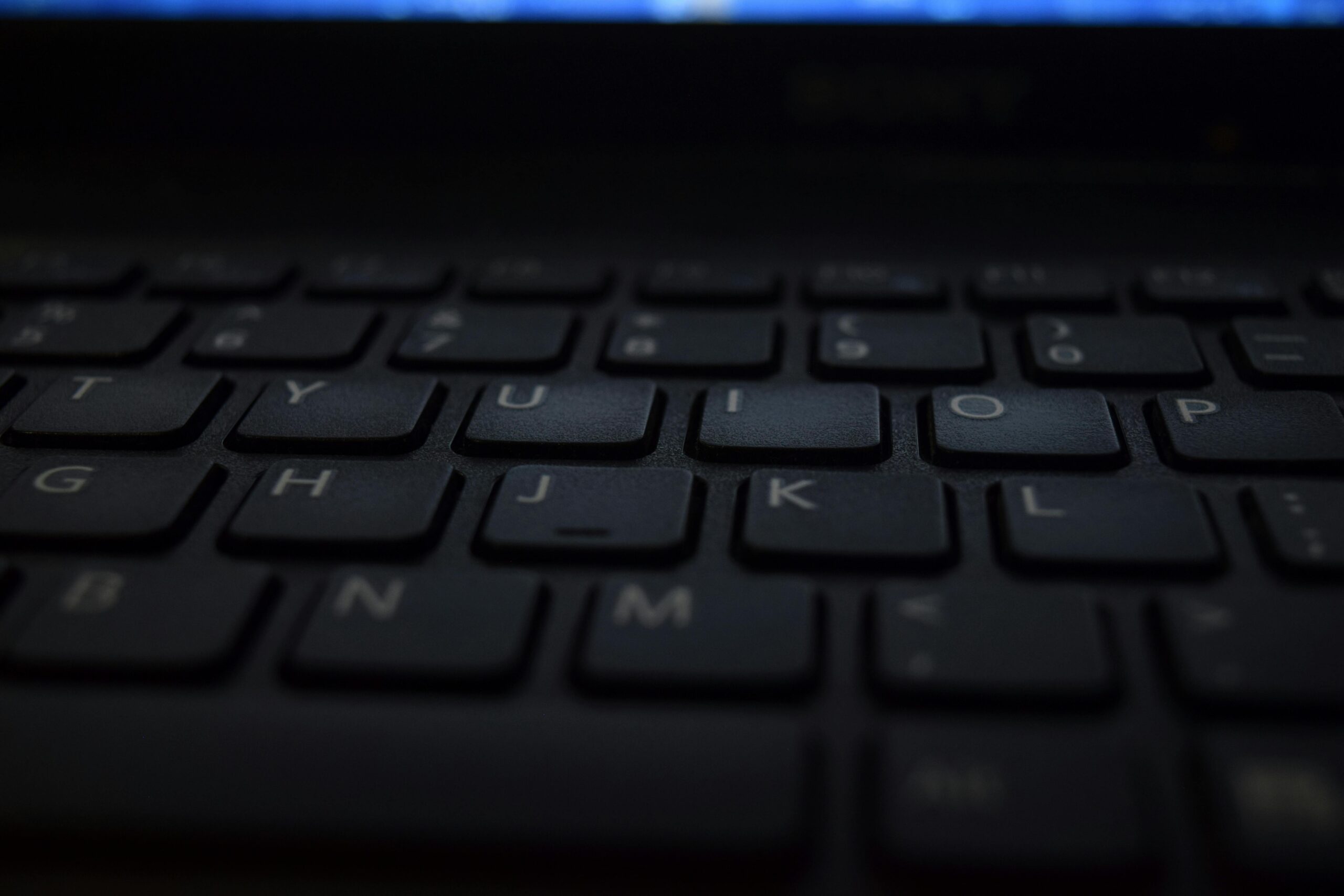 A close-up shot of a modern laptop keyboard with dim lighting, showcasing technology and design.